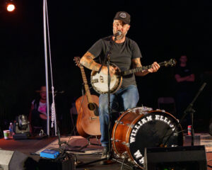 Man on a stage plays the banjo.