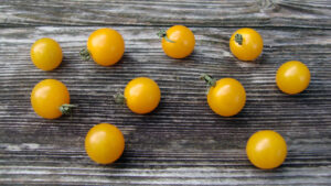 Several yellow cherry tomatoes on a wooden surface