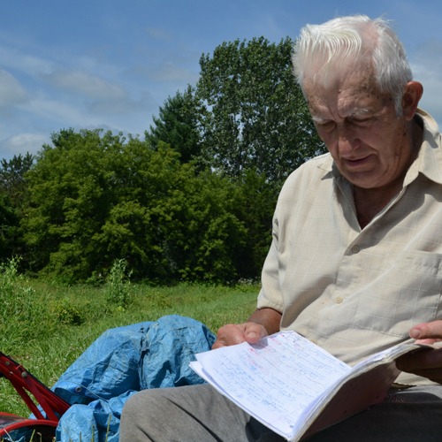 A man sits outside reading a notebook