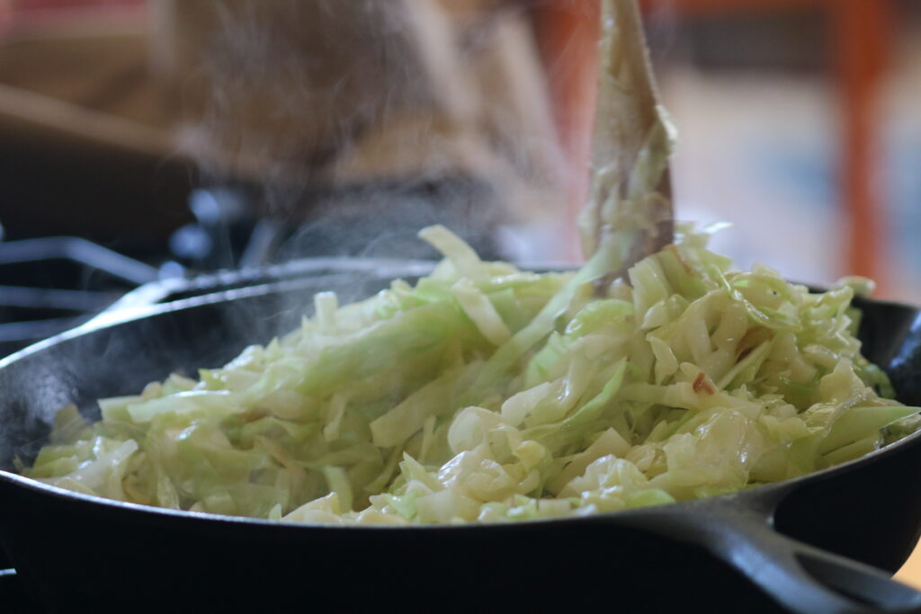 Steaming cabbage noodles in a cast iron skillet