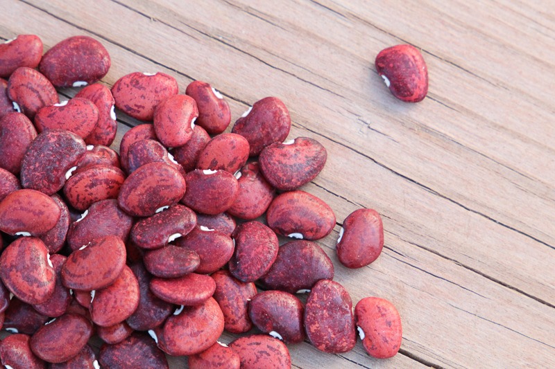 A pile of red lima beans on a wood surface