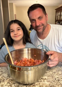 Man and child smile into camera. In front of them is a bowl of Italian Sausage with Crush ‘Ausilio’ Pepper Flakes