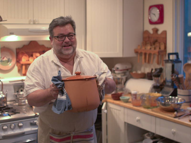 A man holds a large pot in a kitchen
