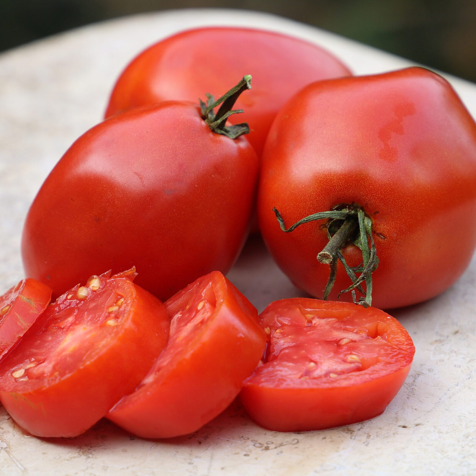 Three red tomatoes and four thick tomato slices