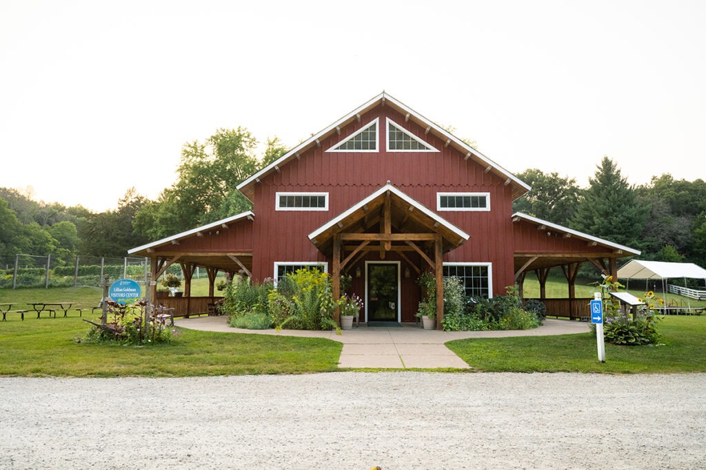 The front of a red building with porches and gardens next to it