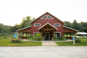 The front of a red building with porches and gardens next to it