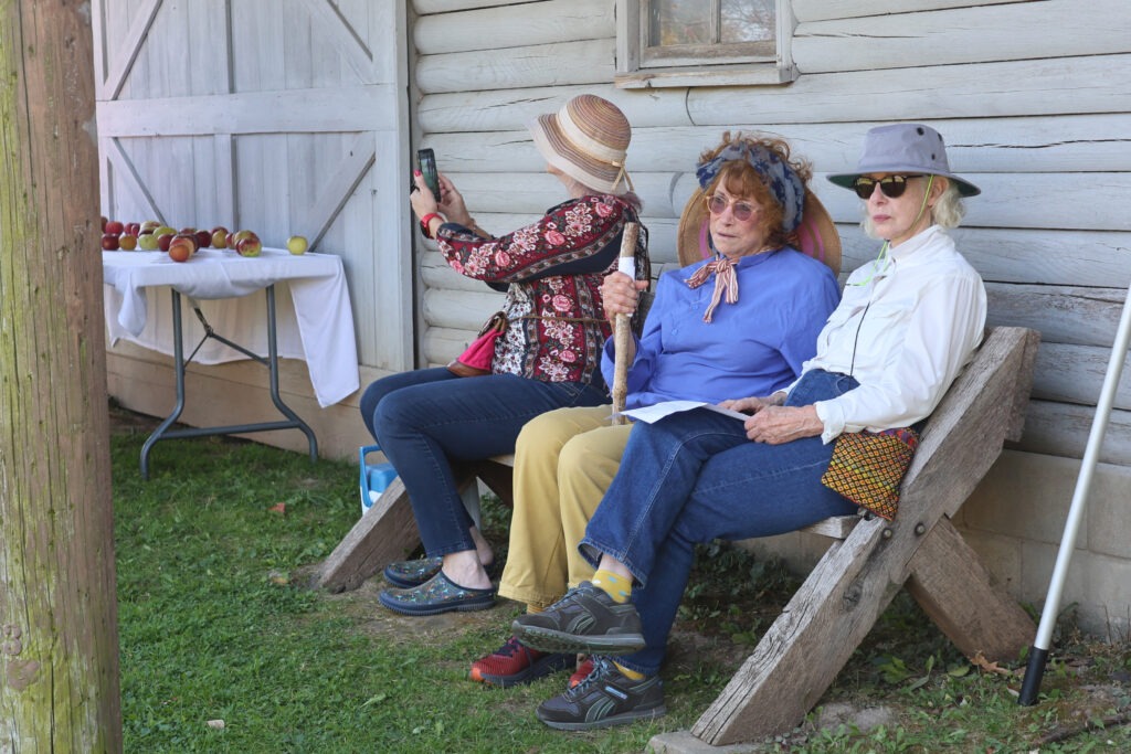 Three women sit on a bench.