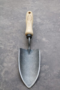 A steel forged trowel with a wooden handle, national weed your garden day