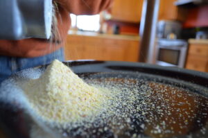 Ground corn coming out of a grinder on to a metal plate