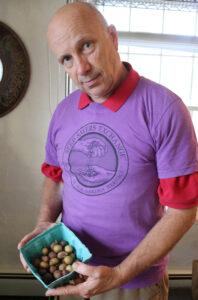 A man in a purple shirt hold a container of small potatoes