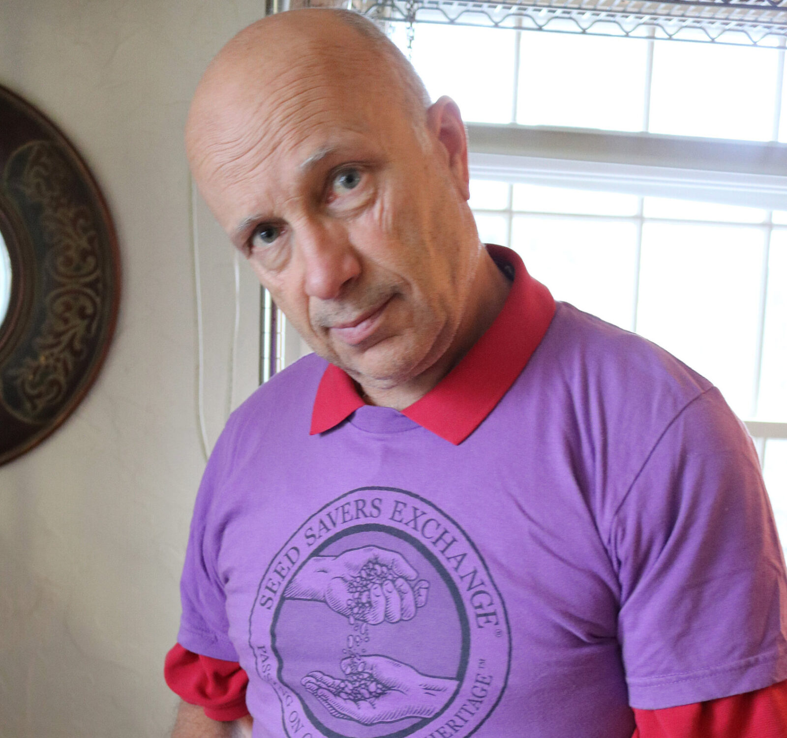 A man in a purple shirt hold a container of small potatoes