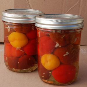 two jars with globular red and yellow pickled vegetables inside