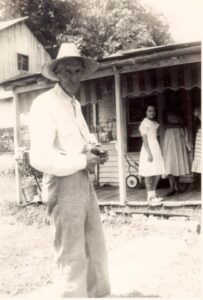 Man in a hat stands looking at the camera.