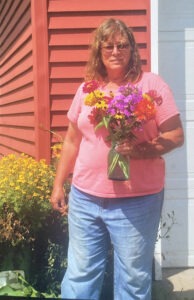 woman in pink, short-sleeved T-shirt and jeans holds a bouquet of fresh flowers