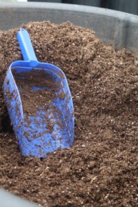 large bin of soil with a large, blue scooper