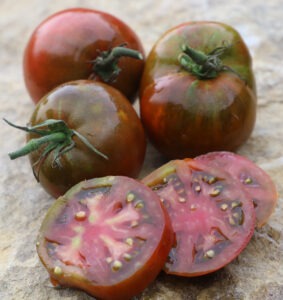 three whole red-black tomatoes and three tomato slices