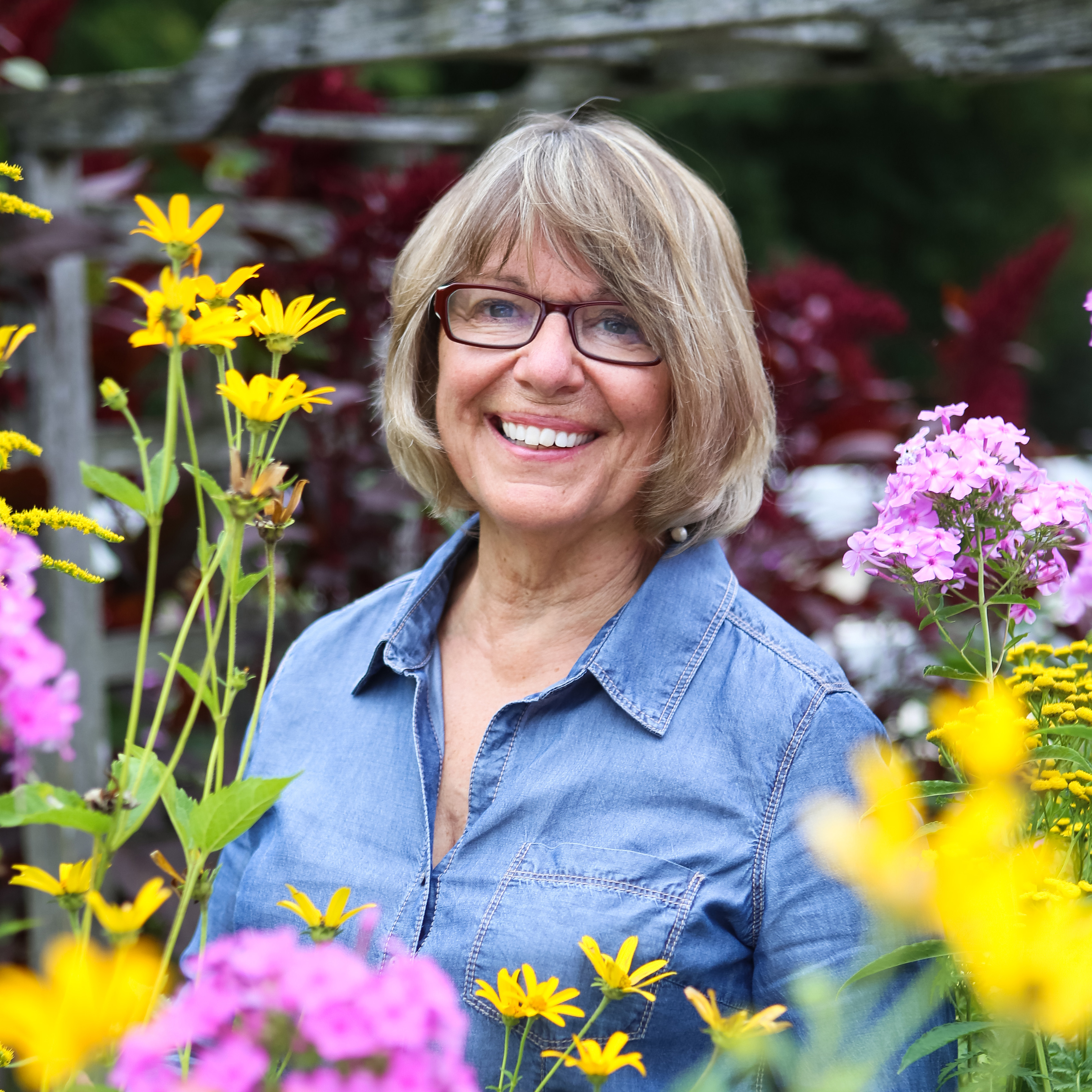 Diane Ott Whealy smiles surrounded by flowers.